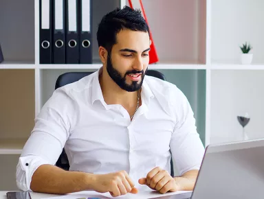 Jeune homme souriant travaillant sur un ordinateur portable dans un bureau lumineux