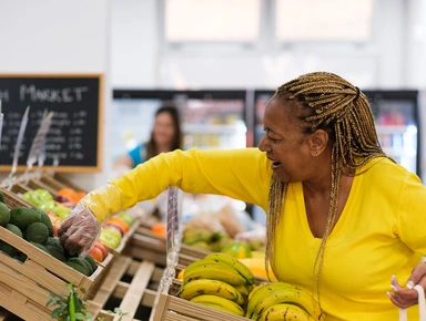 Femme habiléle en jaune avec une tresse achetant un avocat
