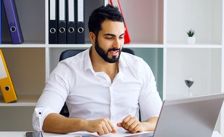Jeune homme souriant travaillant sur un ordinateur portable dans un bureau lumineux