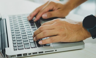 Deux mains tapant sur un clavie d'ordinateur portable